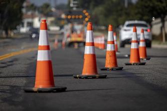 Alt: Image of a line of orange traffic cones on a road.