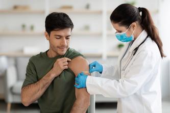 A medical worker places a bandage on a man after vaccination.