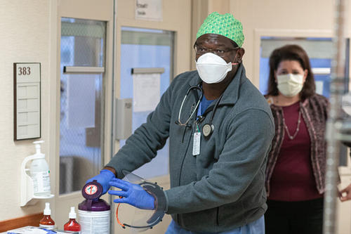 A man and a woman, both wearing masks, in a health care setting.