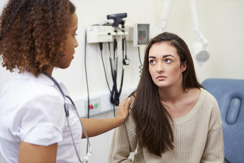 A female doctor talks to an adolescent girl.