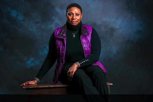 Rhonda Franklin wearing bright purple winter vest and black clothes in front of dark blue cloudy background