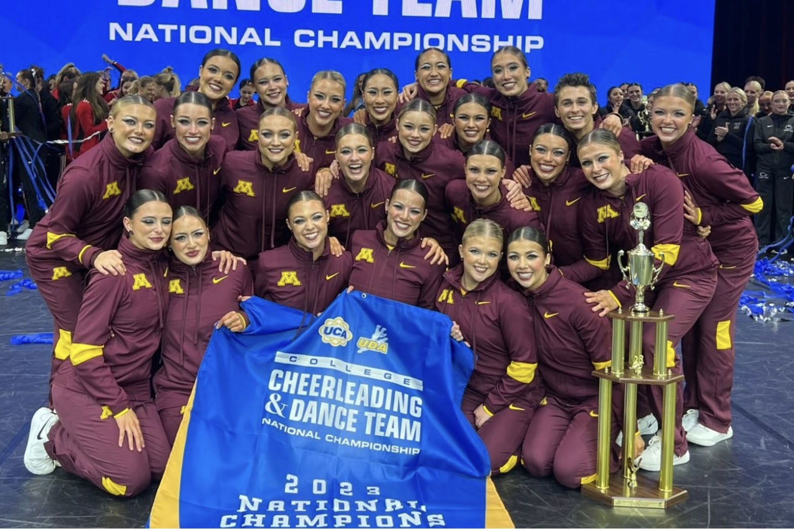 The national champion dance team poses with a banner and trophy.
