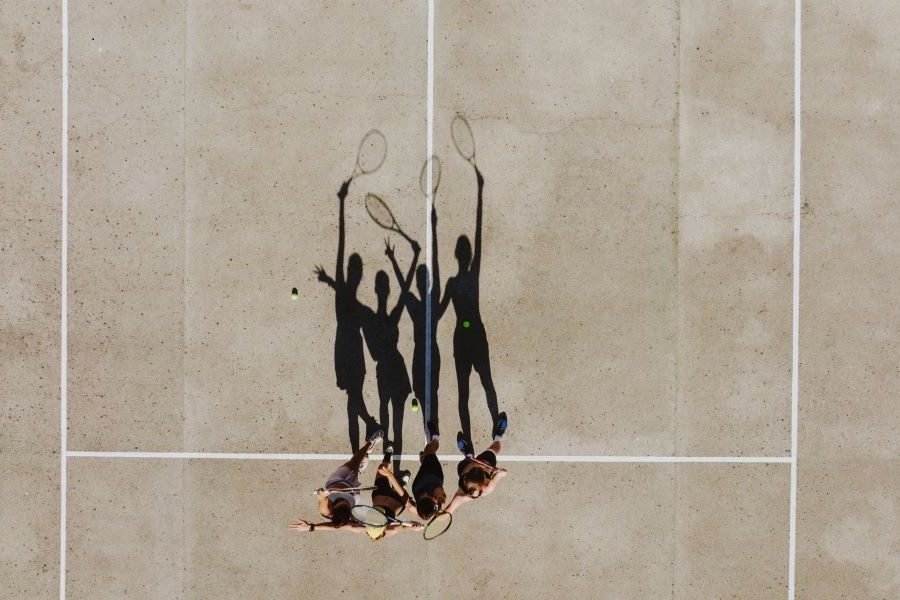 Four women friends on a tennis court from above.