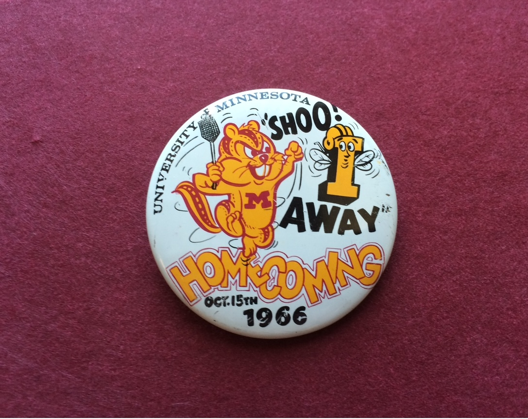 A Homecoming button from 1966 with the slogan "Shoo! I Away" and Homecoming October 15, 1966.