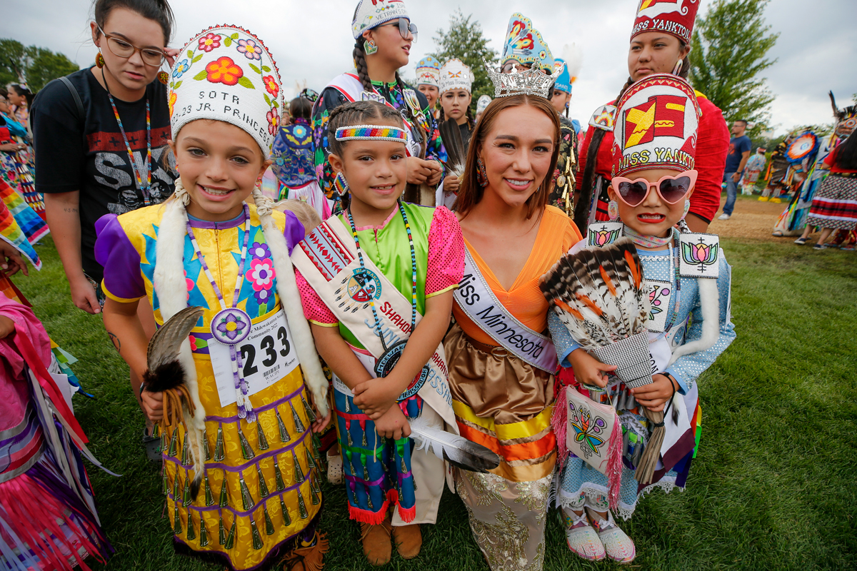 Rachel Evangelisto posing with children wearing traditional dress at the powwow