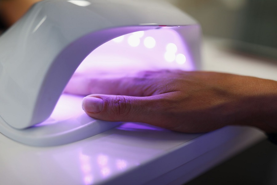 Close-up of woman putting hand under UV lamp.