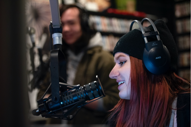 Female student speaking into radio microphone with another person in the background
