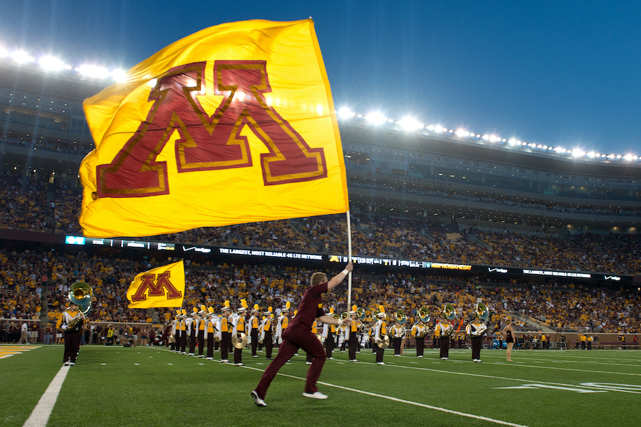U of M flag and marching band in the stadium at night