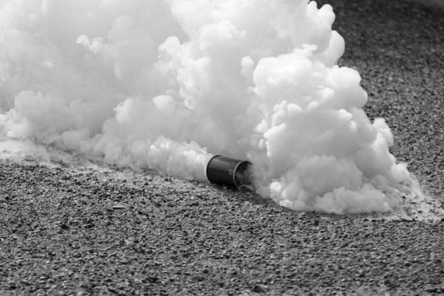 Can of tear gas smoking on pavement