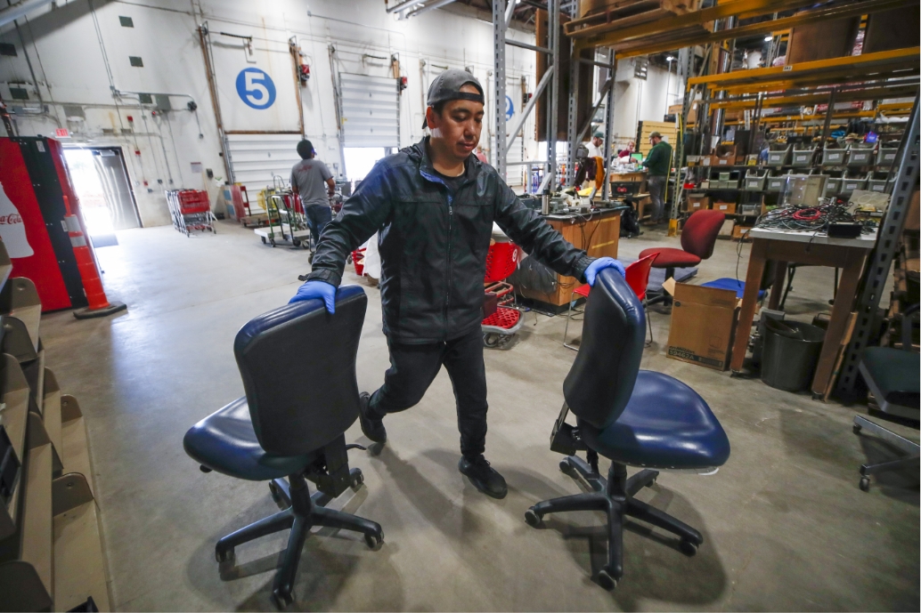 student worker Arman Kurmanbayev moving chairs around in the warehouse