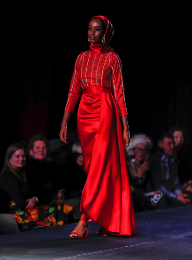 Model wears shiny red skirt with red long-sleeved top with sliver stripe details