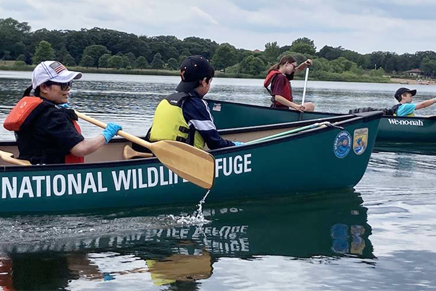 Participants in a nature program paddle canoes on a body of water.
