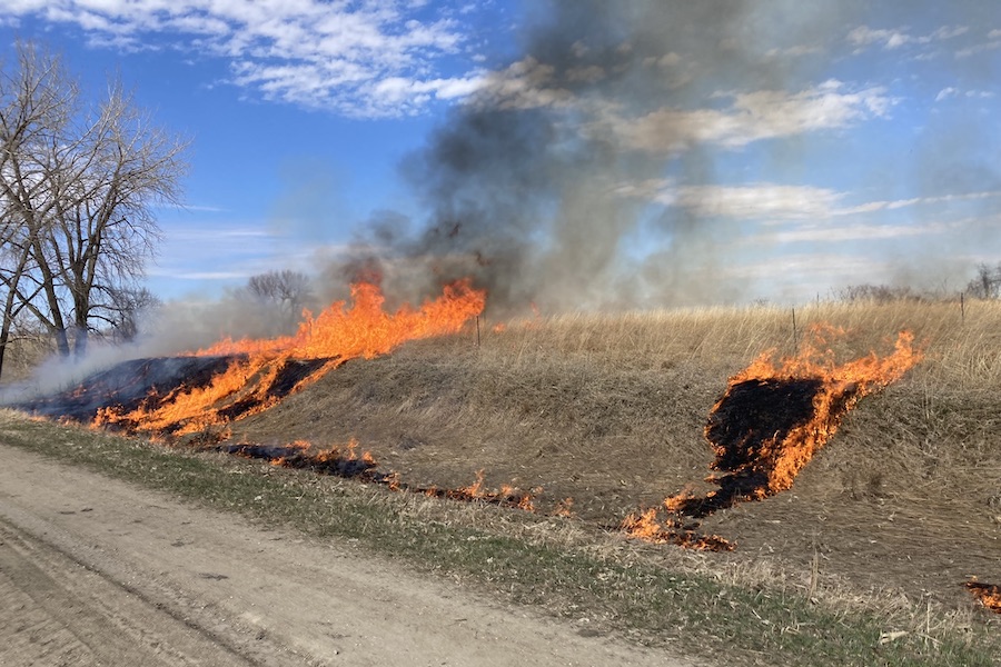 A small stretch of brown prairie burns under a blue sky.