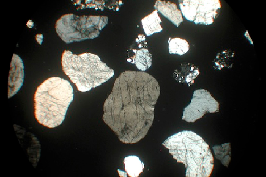 Shocked quartz grains of various sizes and shades of gray, as seen under a microscope