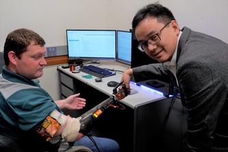 Two men shaking hands, one man has a robotic arm