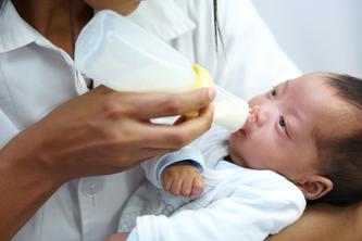 Image of a healthcare worker bottle feeding a baby with a cleft lip.