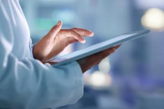 Person in a lab coat using an electronic tablet.
