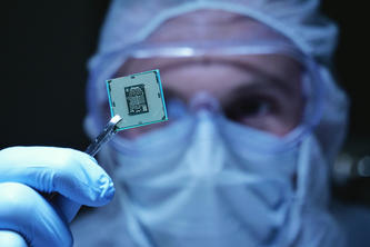 A medical scientist holds up a microchip with tweezers