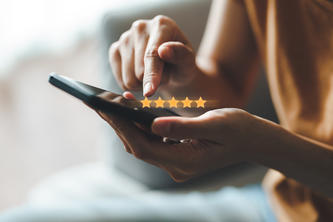 Hands enter a five-star rating on a cell phone app.