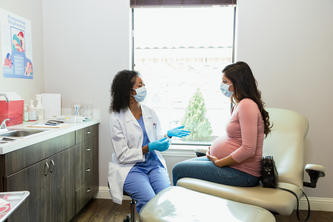 Pregnant person speaking with a doctor in a medical setting
