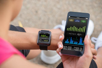 A jogger looks at exercise data on a phone and smart watch