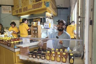 Joshua Munoz smiles behind a selection of honey at the Minnesota State Fair.