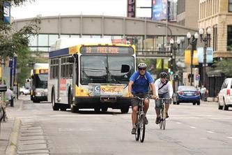 Two bicyclists cruise in front of a Metro Transit bus in Minneapolis.