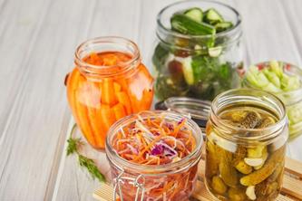 Image of different kinds of fermented vegetables in multiple jars. 