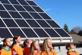Students standing  in front of a solar array on a sunny day. 