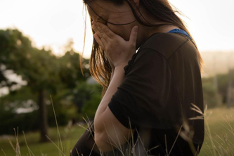 Pregnant woman standing in a field crying