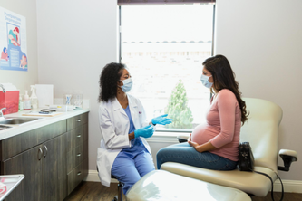 Pregnant person speaking with doctor in medical setting