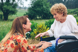 Elderly white woman in a wheelchair speaking with younger white woman