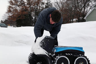 Max Minakov adjusts his snow robot outdoors in the snow