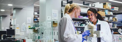 Two female student wearing lab coats working in scientific lab
