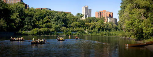 students canoeing on Mississippi river with buildings rising above trees