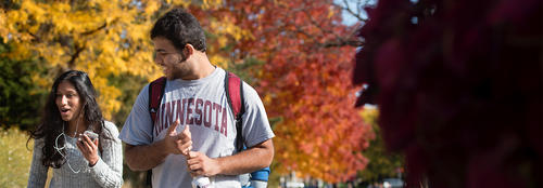 Students walking on campus in autumn with leaves changing color in background
