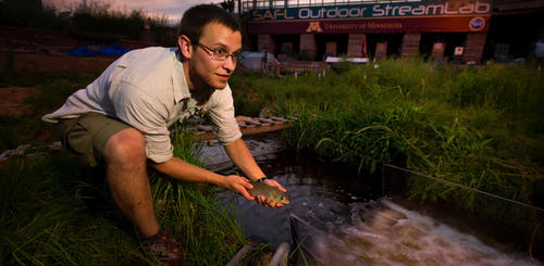 researcher hold small fish at the stream lab