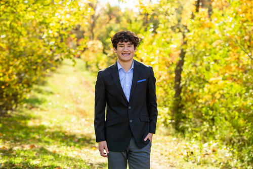 Student Drake Pham poses in a forest along a walkway wearing professional attire