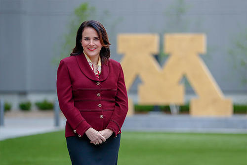 University of Minnesota President Joan Gabel, in a Maroon blazer with black pants, poses standing for a portrait in front of a Gold, Block M statute on the Twin Cities campus