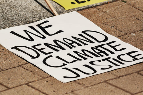 protest sign on stone walkway reading "We demand climate justice"