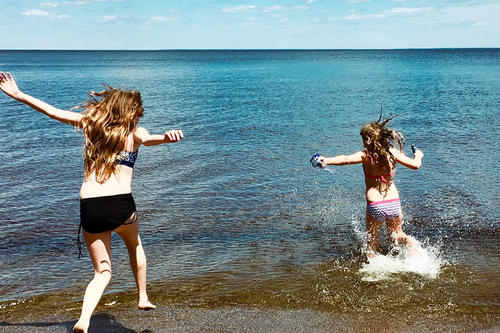 Two girls jumping into a lake