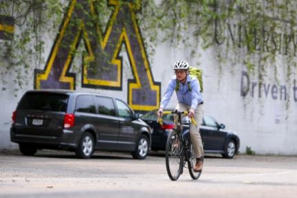 cyclist wearing helmet with UMN block M logo painted on wall in background