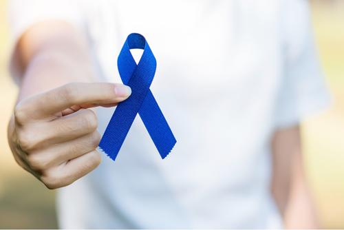 Image of hand holding a blue colorectal cancer ribbon