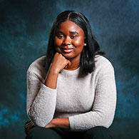 Gbemi Oyetunde wearing light gray sweater in front of dark blue cloudy background
