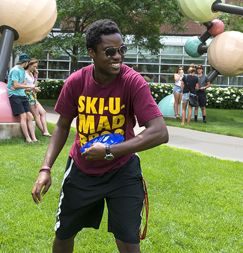 A black student about to throw a frisbee in front of the Molecular and Cellular Biology building