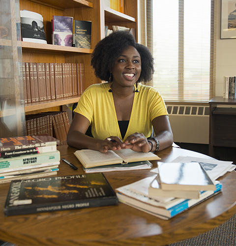 A black student speaking while studying books laying on a table