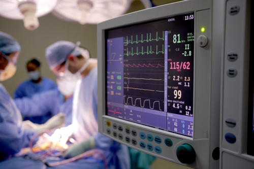Operating room with vitals monitor on the right and doctors operating on the left