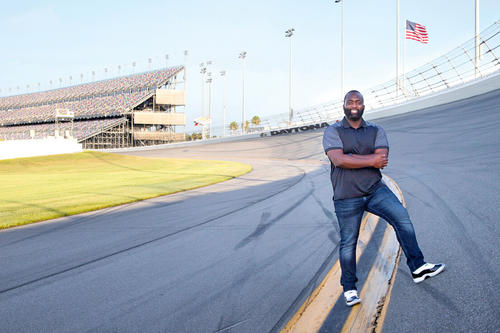 On a sunny day in Florida, Hakeem Onafowokan poses on the track at Dayton, with grandstand in the background.