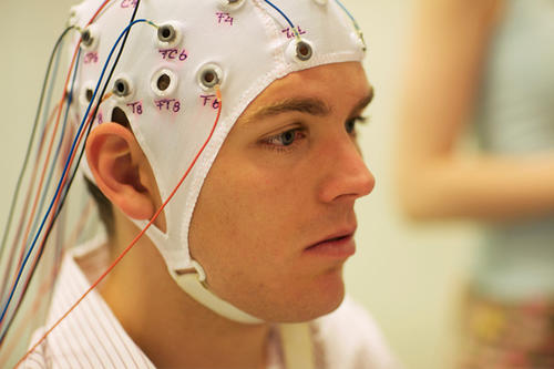 A man wearing a device on his head with wires leading to it