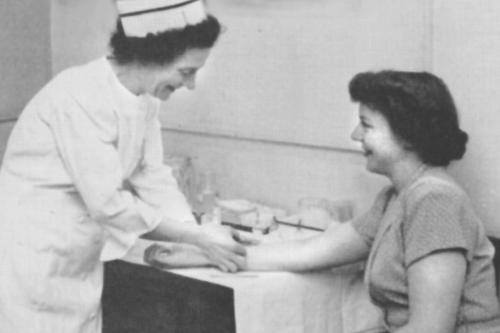 A nurse tends to a female student many years ago.